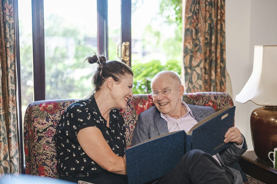 Elderly man looking at a photo album with a caregiver